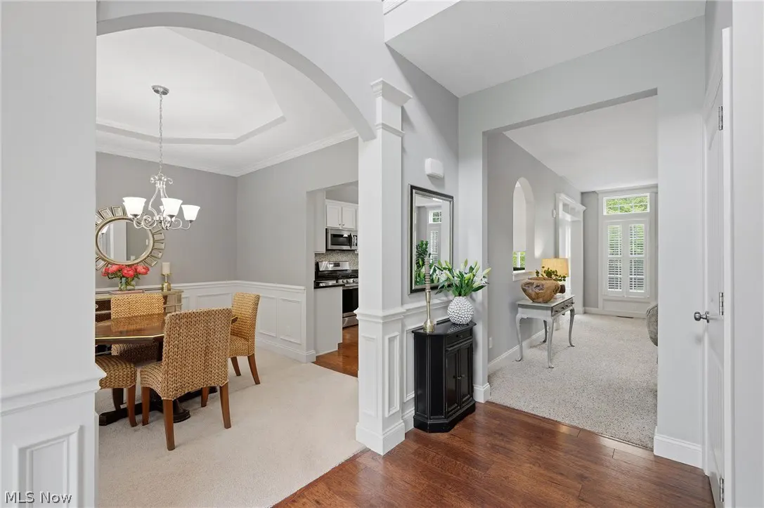 Interior view of a home featuring a dining room with a table, chairs, and chandelier. A hallway leads to another room.
