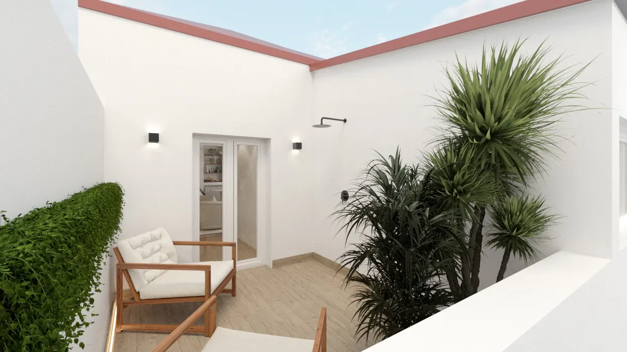 A bright courtyard with white walls, wood chairs with white cushions, and green plants. A shower head is mounted on the wall.
