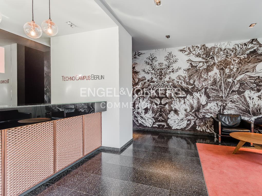 Office lobby with a rose gold reception desk, black speckled floors, and a black and white floral mural.