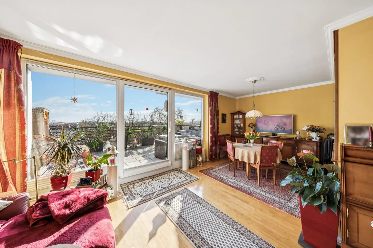 Bright living room with a dining area, wood floors, and a large sliding glass door to a rooftop patio.