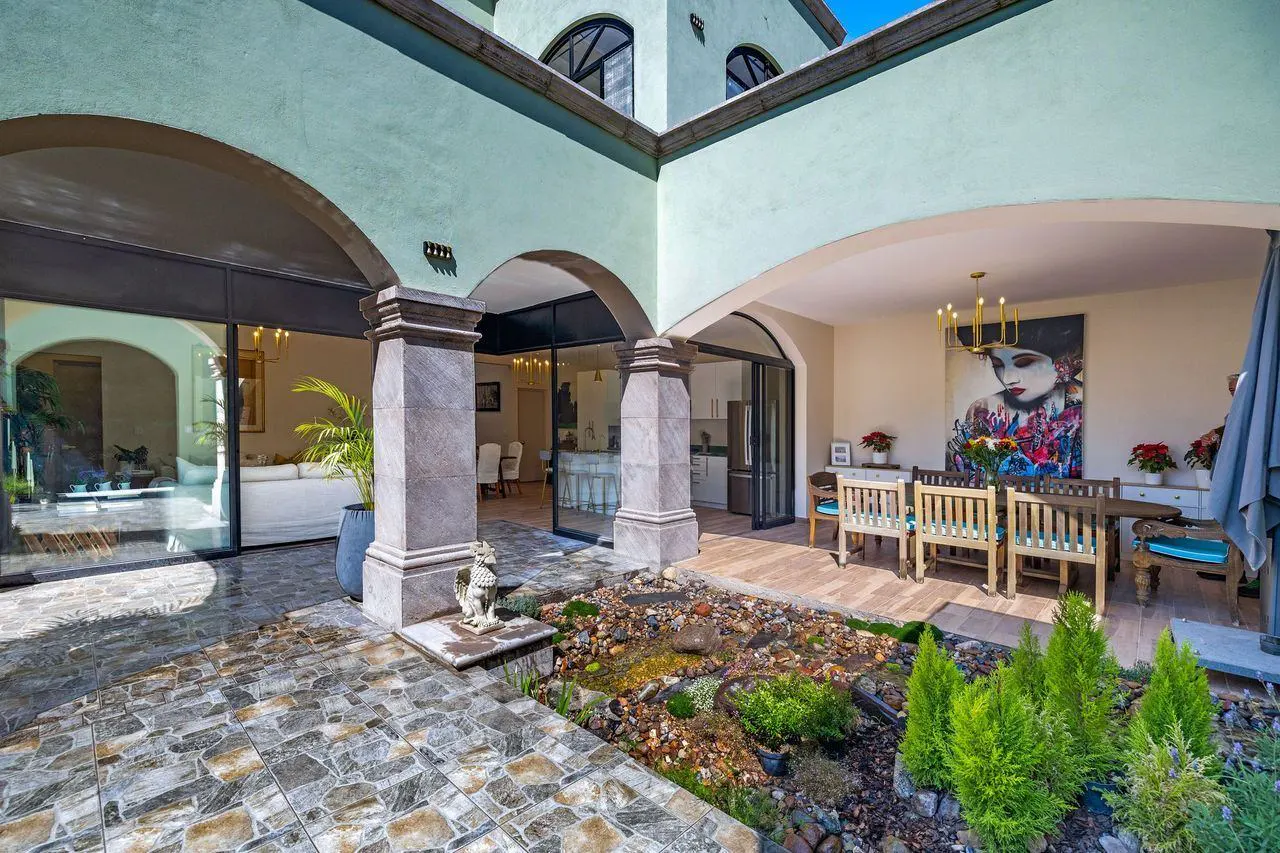 Outdoor patio with stone arches, tiled floor, and a rock garden. Dining table and chairs are visible in the background.