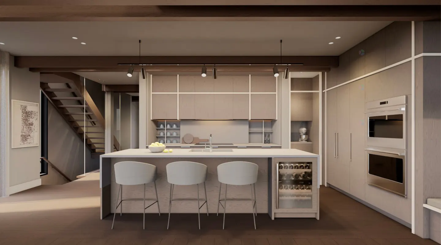 A modern kitchen with a white island, three stools, and a wine cooler. Built-in ovens and cabinets line the wall. A staircase is visible in the background.
