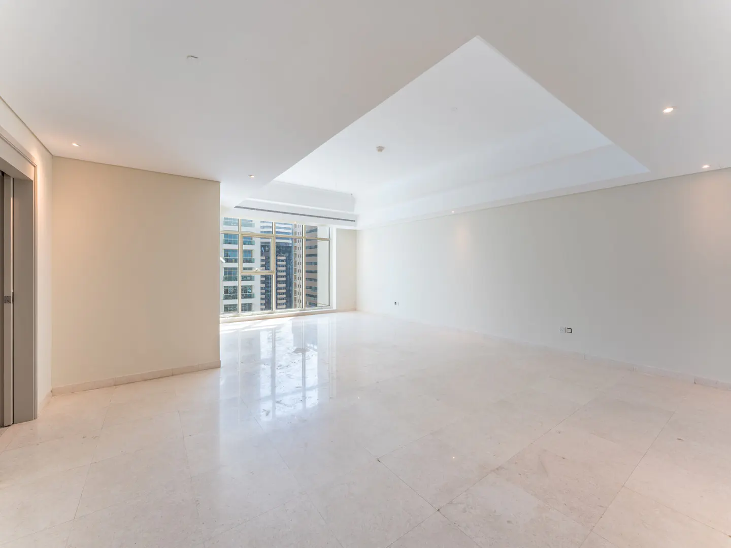 Empty room with marble floors, white walls, and a large window showing city buildings.