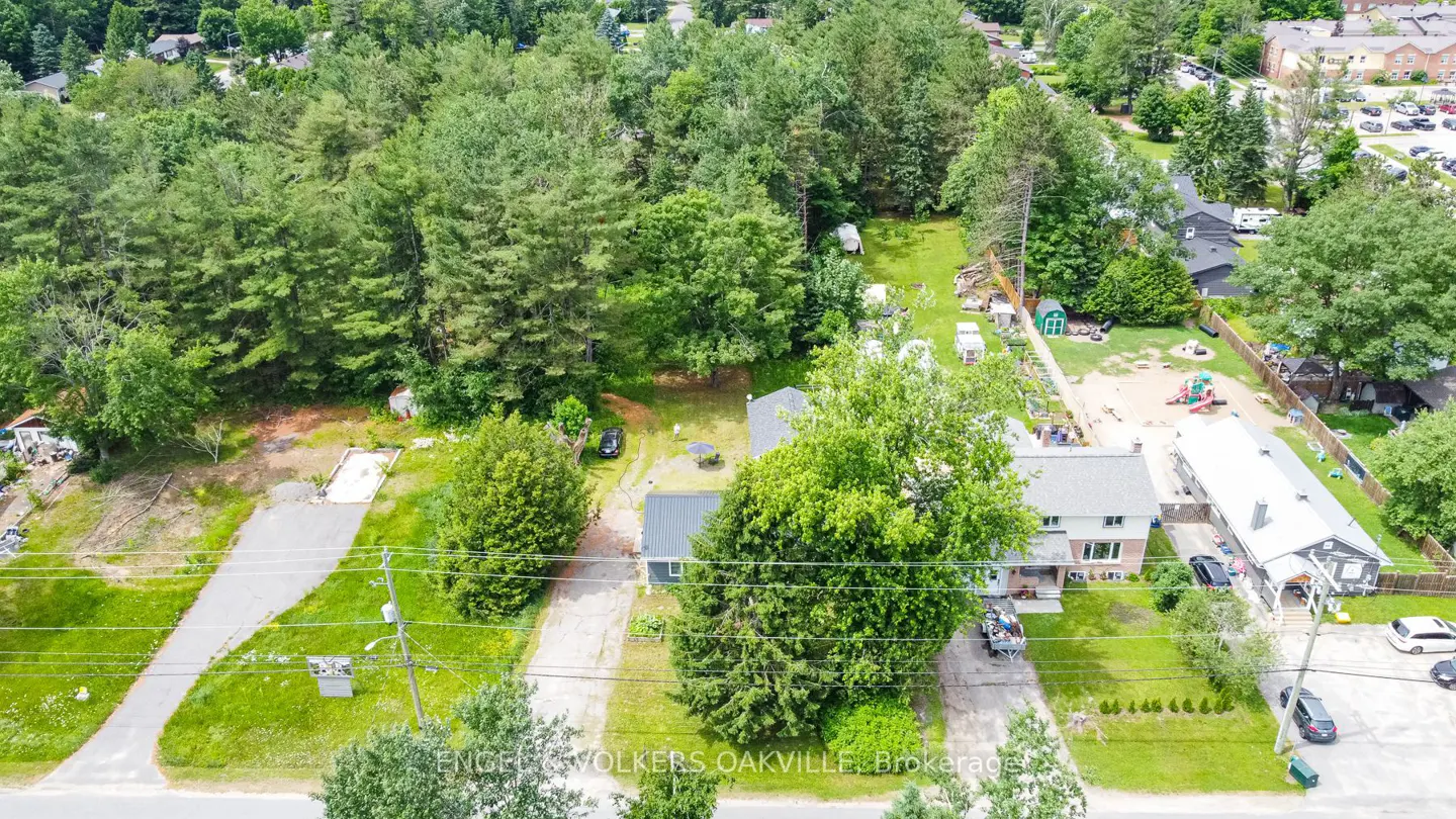 Aerial view of a property with a house, trees, and a long driveway. A playground is visible in the background.