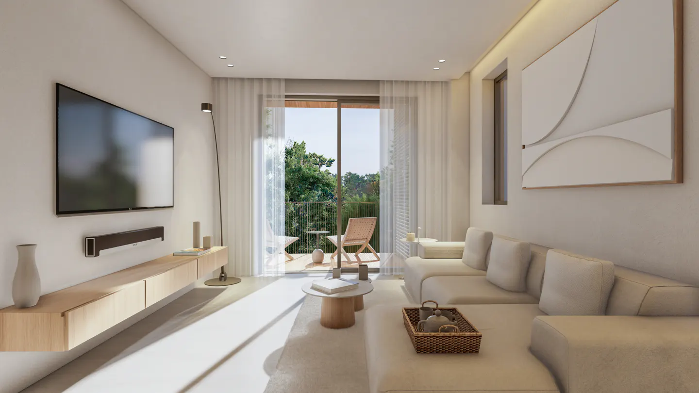 Bright living room with a TV, light wood console, and a white sectional sofa. A balcony with a chair is visible through sheer curtains.