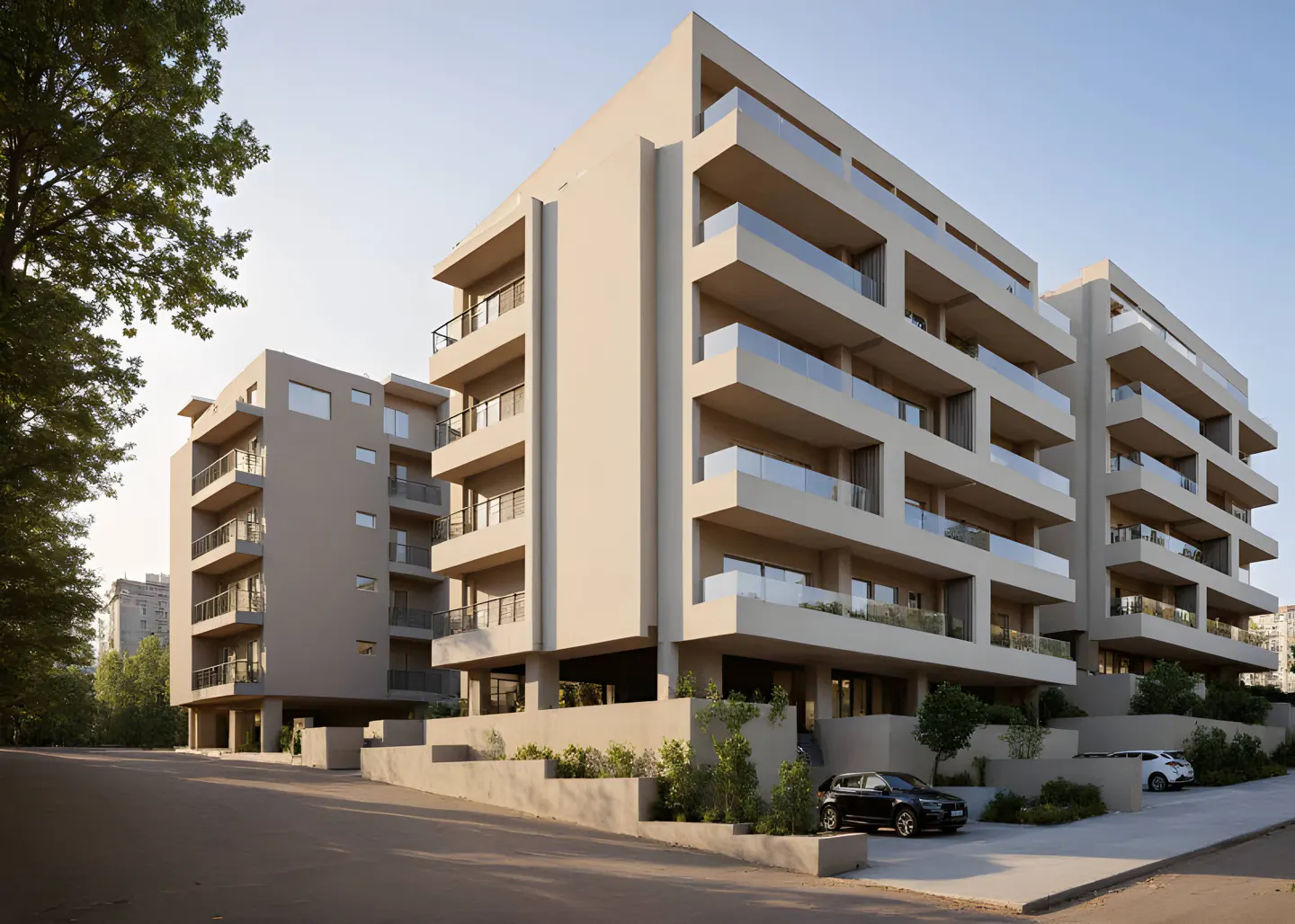 Modern beige apartment buildings with glass-railed balconies, surrounded by trees and a parking area with cars.