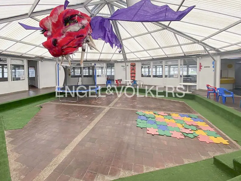 Indoor playroom with a red dragon decoration hanging from the ceiling, a trampoline, and colorful puzzle pieces on the floor.