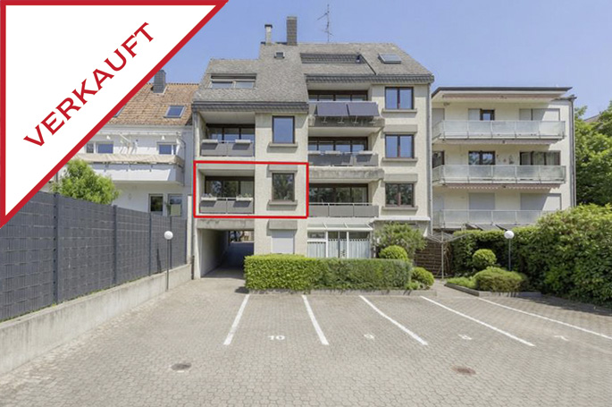 Multi-story apartment building with a red-framed balcony and a "VERKAUFT" (sold) banner in the corner. [AI-generated text]