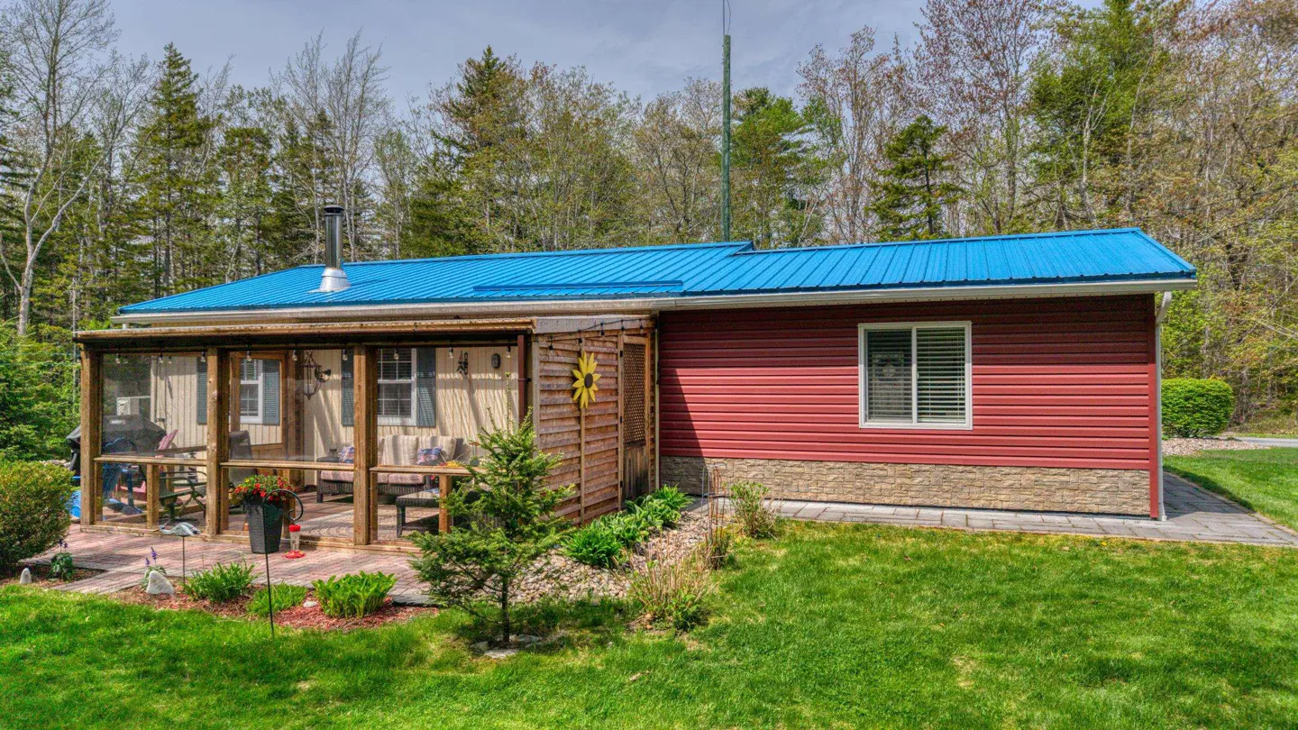 Exterior view of a red house with a blue metal roof and a screened-in porch.