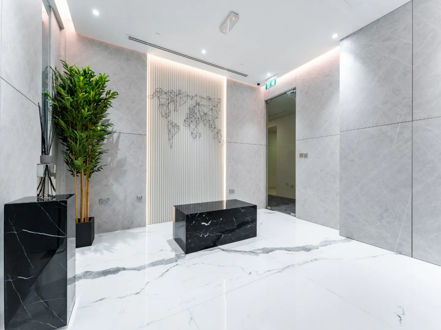 Modern office lobby with white marble walls, black marble furniture, a potted plant, and a wireframe world map wall art.
