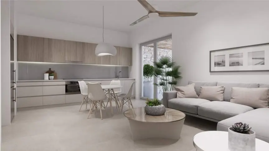 Open-concept living space with a kitchen, dining area, and living room. Gray sofa, white walls, and light wood cabinets.