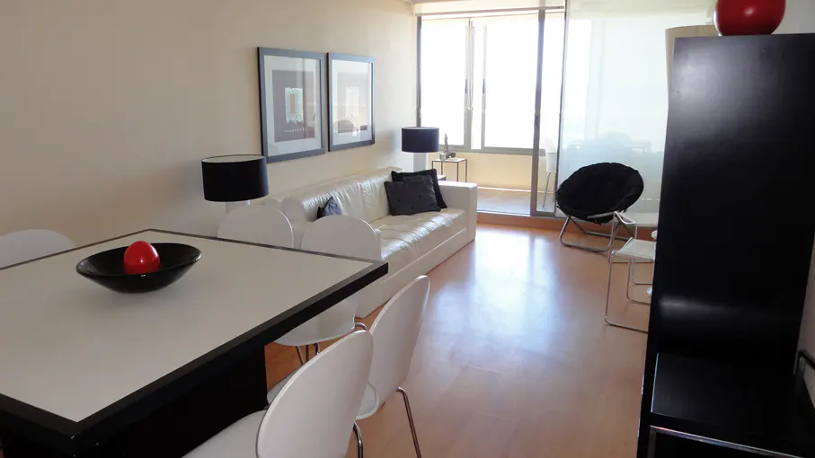 Living room with white sofa, black pillows, white table and chairs, black lamps, and a black papasan chair.