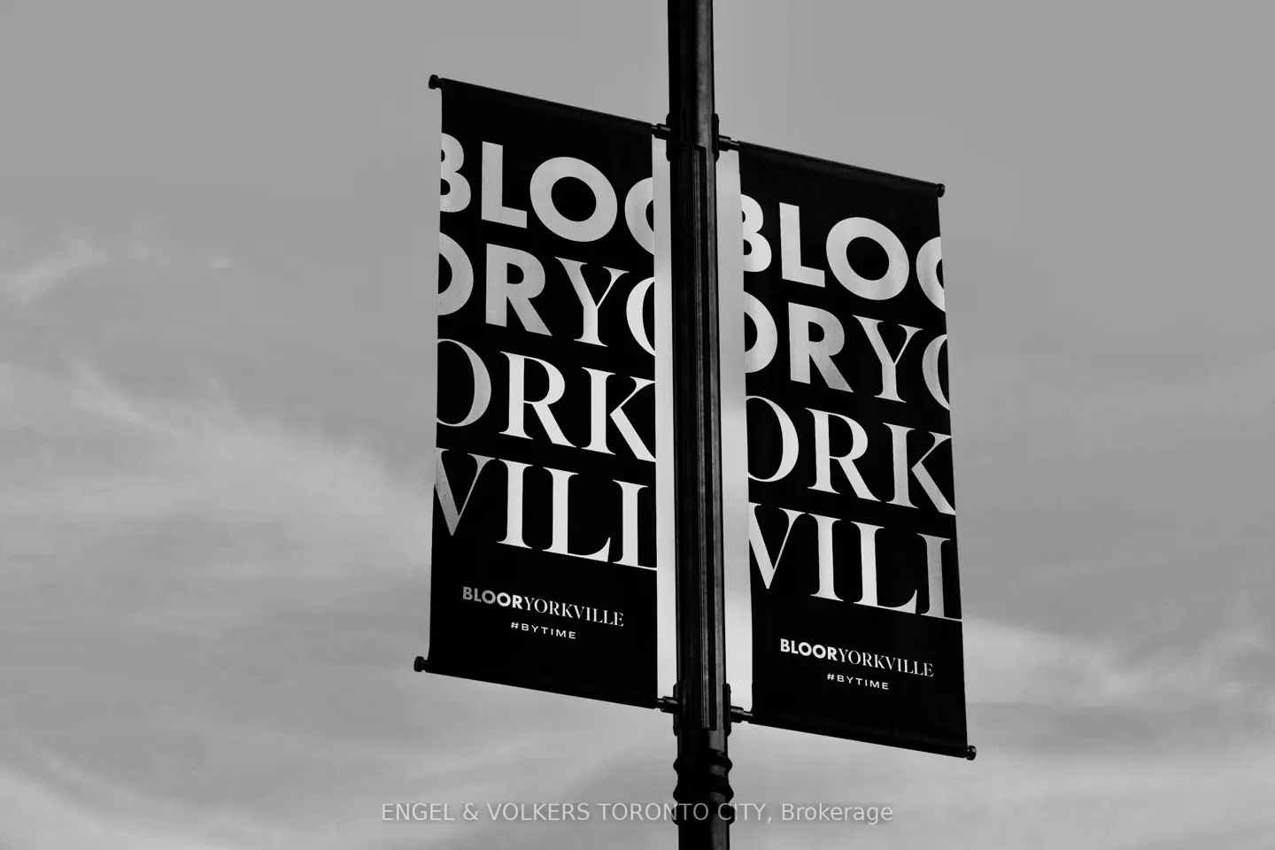 Black and white shot of two black banners on a pole, reading "BloorYorkville" in white letters. #BYTIME is printed below.