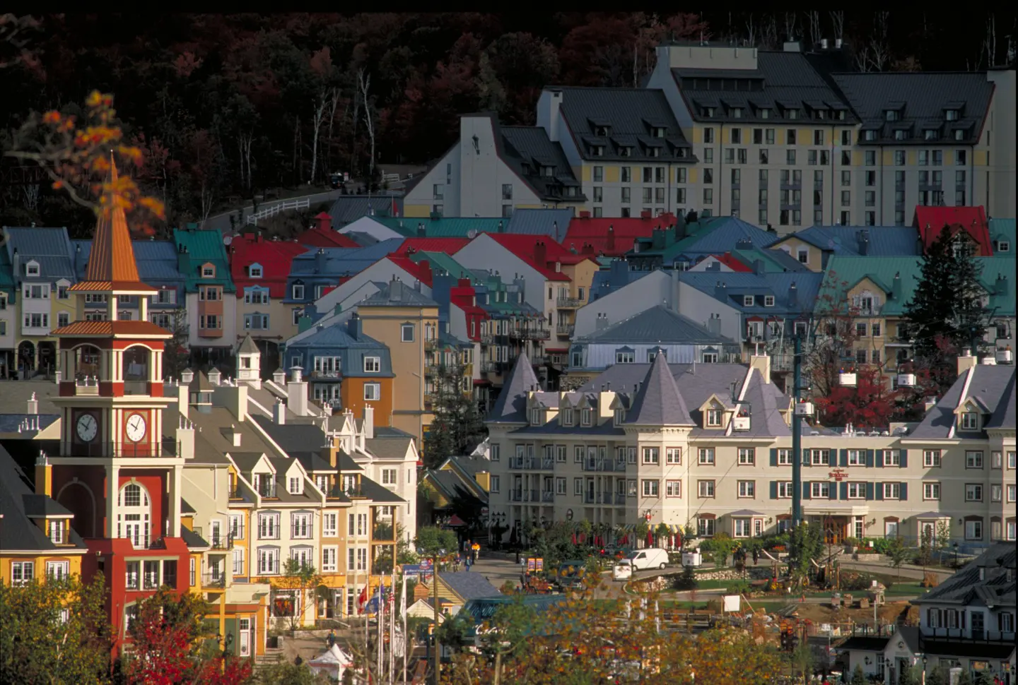 View of Mont-Tremblant village with colorful buildings and a clock tower. Forest in the background.