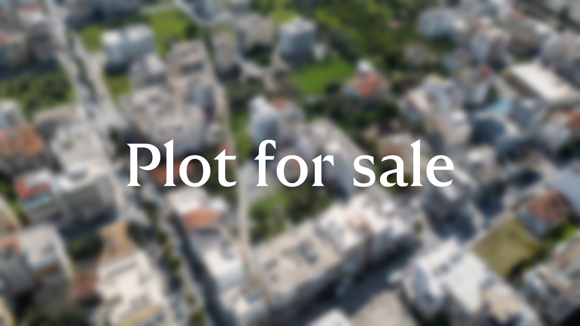 Aerial view of a residential neighborhood with a green plot of land in the center, overlaid with the text "Plot for sale." [AI-generated text]