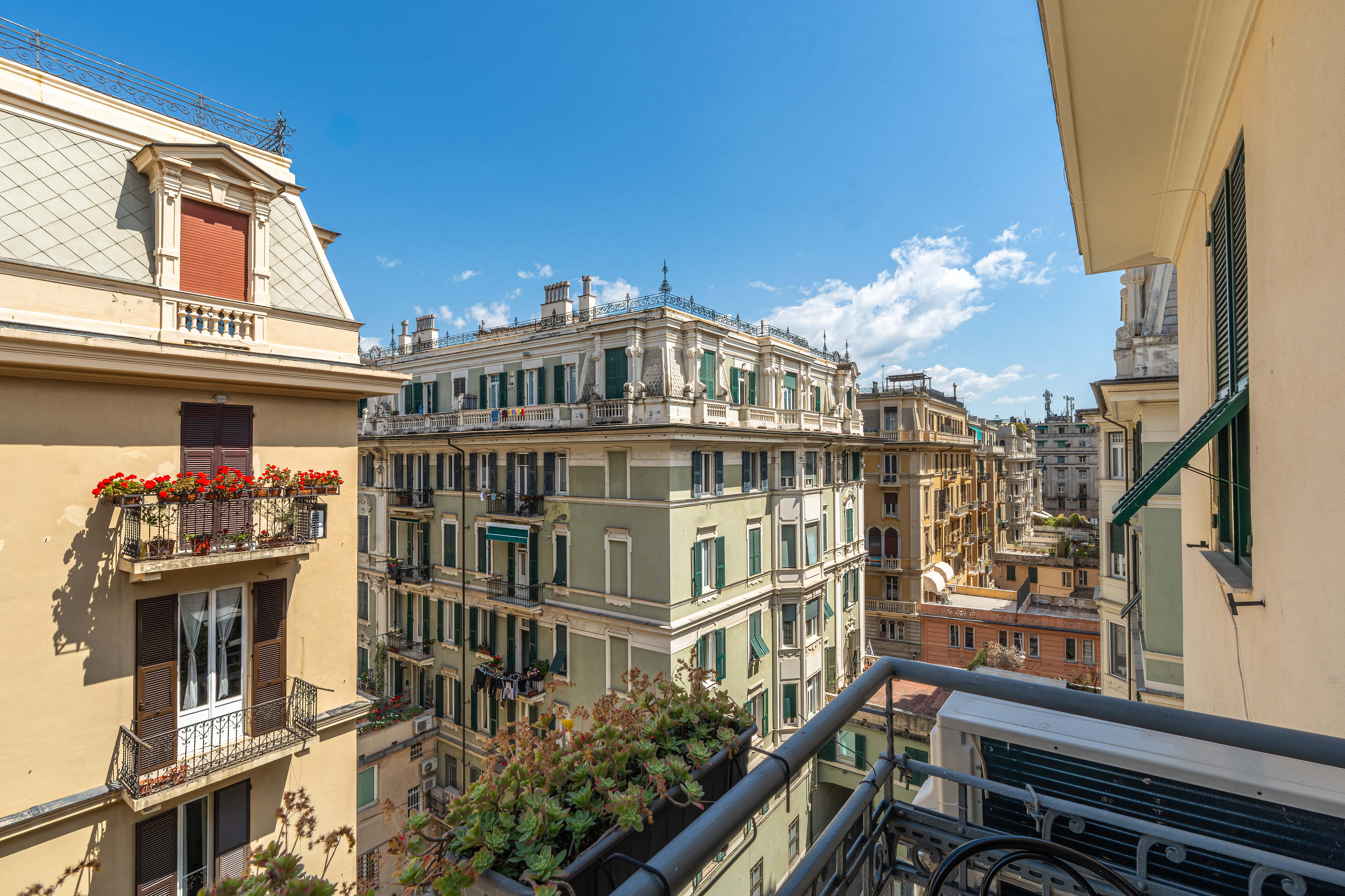 View from a balcony overlooking European buildings under a blue sky with white clouds.