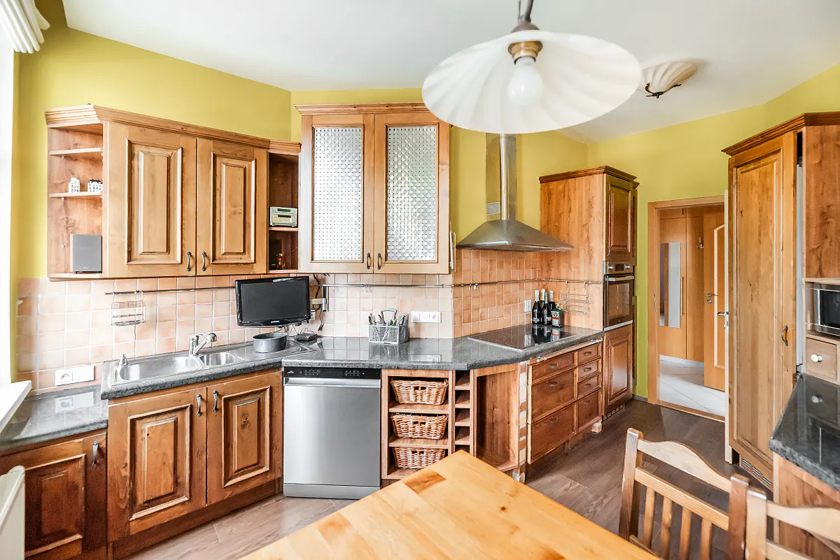 A kitchen with wooden cabinets, stainless steel appliances, and yellow walls.