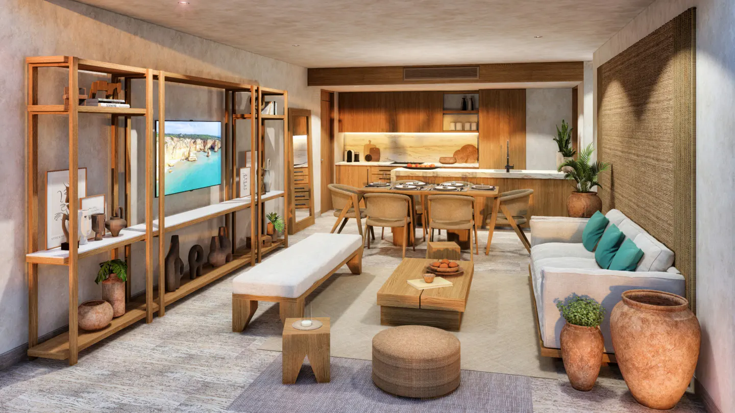 Open-concept living space with wood shelving, TV, dining table, and white sofa with teal pillows. Neutral tones and natural light.