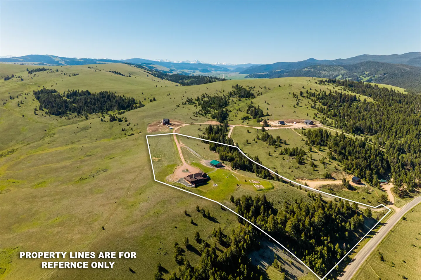 Aerial view of a rural property outlined in white, featuring a house and outbuildings amidst rolling green hills.