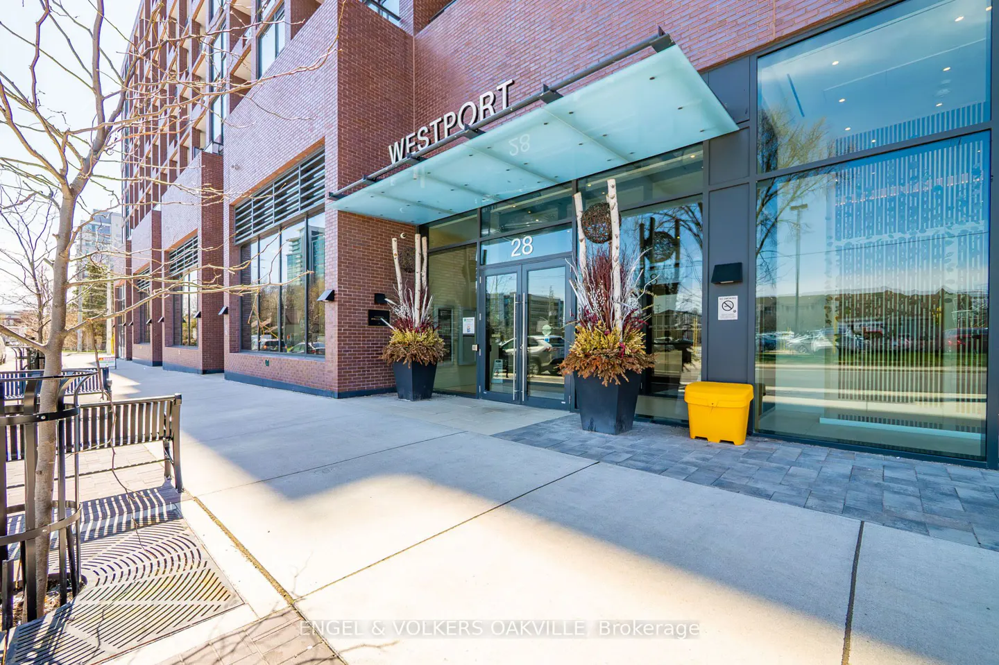 Exterior of the Westport building with glass doors, planters, and a yellow bin.