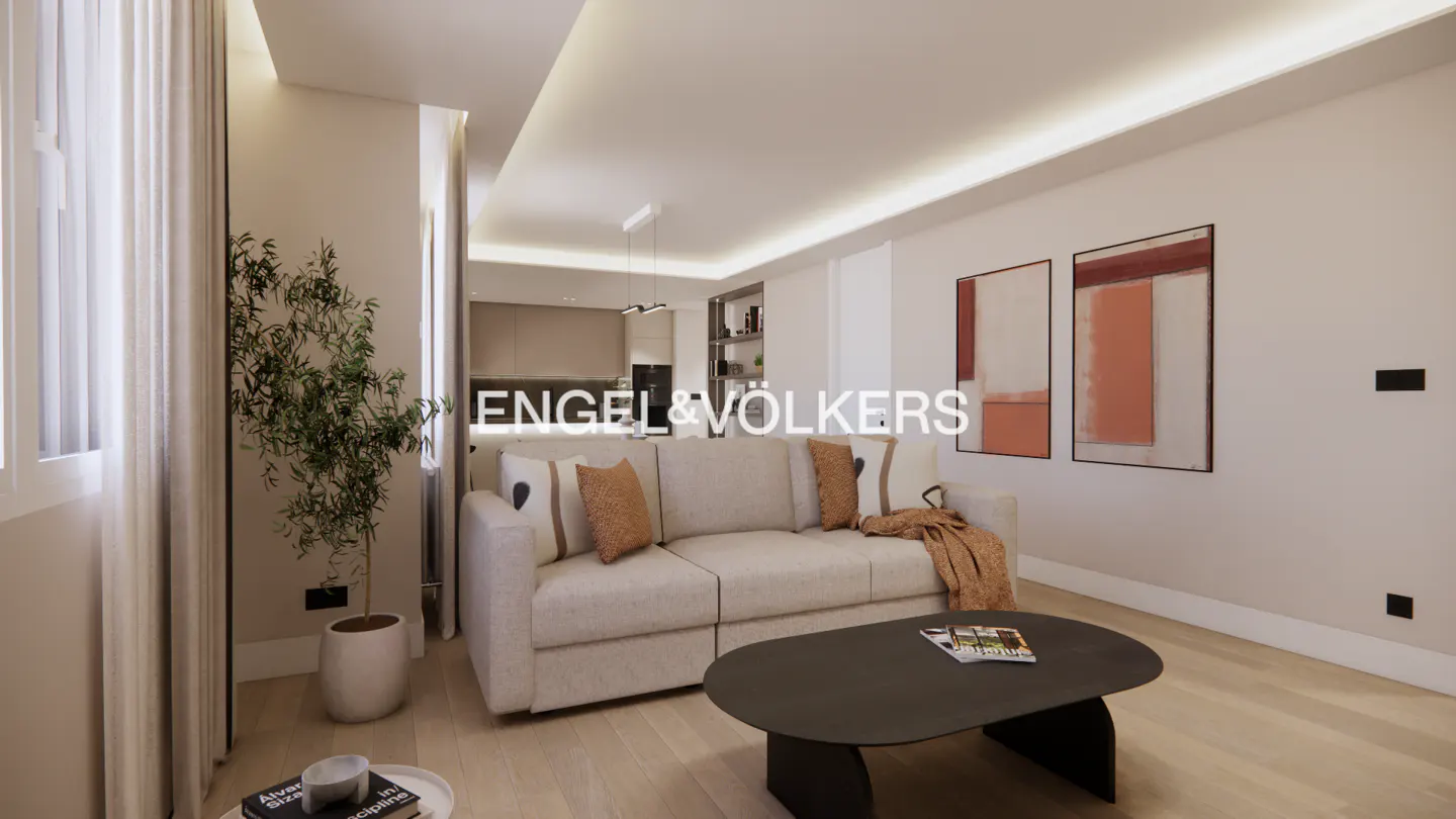 Modern living room with a beige sofa, oval coffee table, potted plant, and abstract wall art in a neutral-toned apartment.