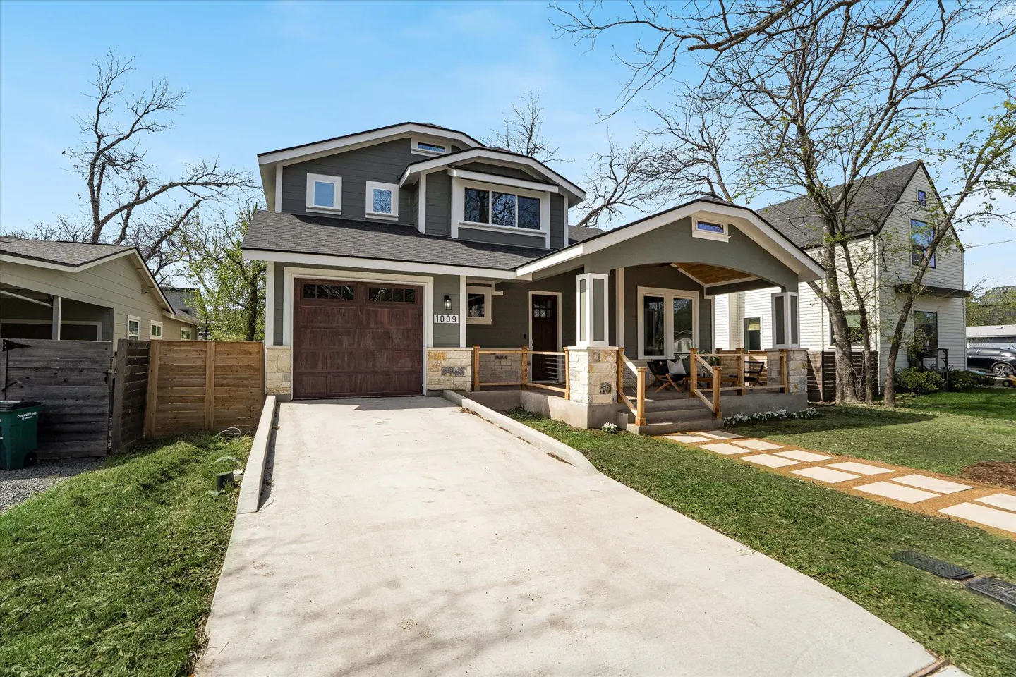 Two-story gray house with a brown garage door, a front porch, and a concrete driveway.