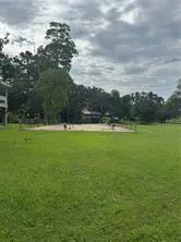 A large green lawn with trees and a cloudy sky in the background.