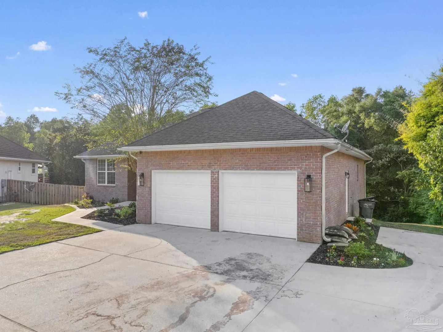 A brick house with a two-car garage and a gray roof on a sunny day.