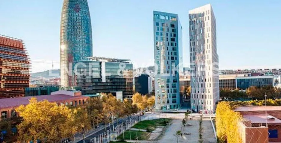 Barcelona cityscape featuring modern architecture, including tall, geometric buildings and the Agbar Tower under a clear blue sky.