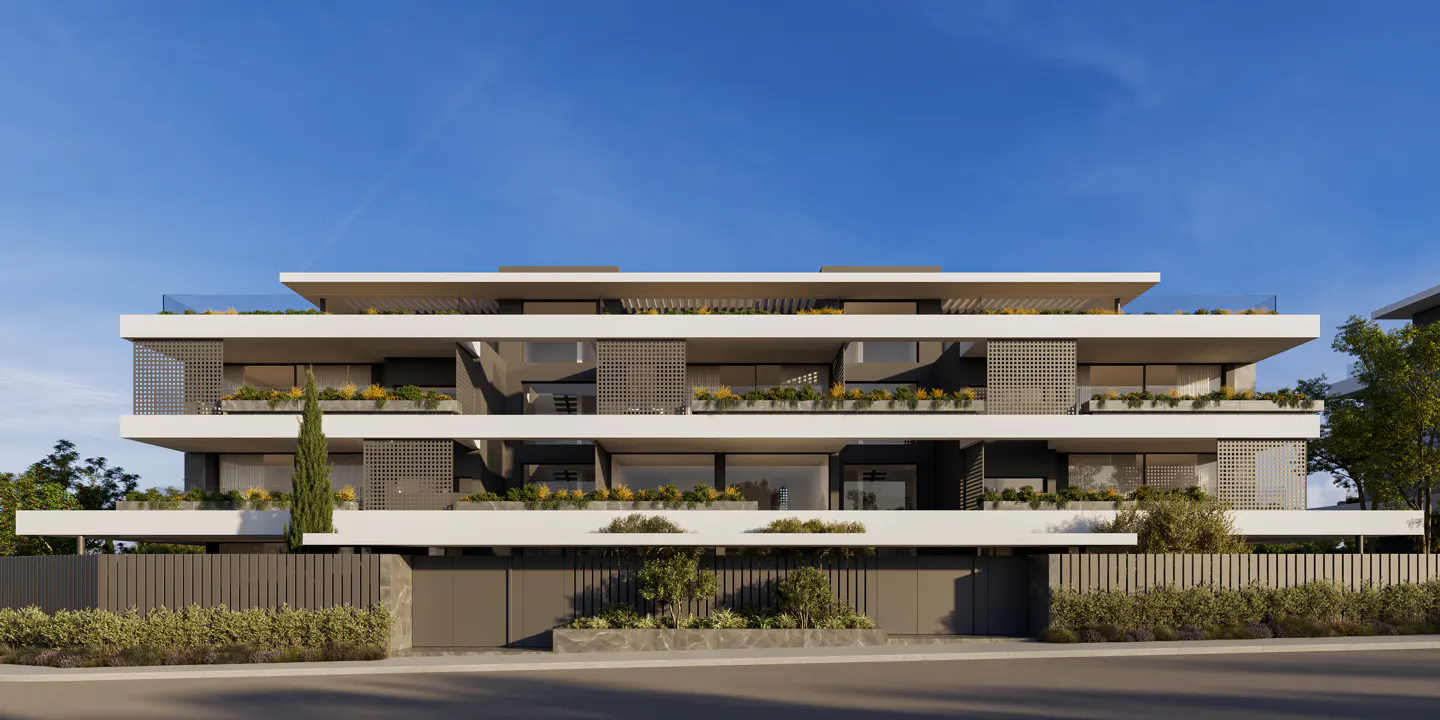 Modern three-story apartment building with white balconies and gray accents under a blue sky.