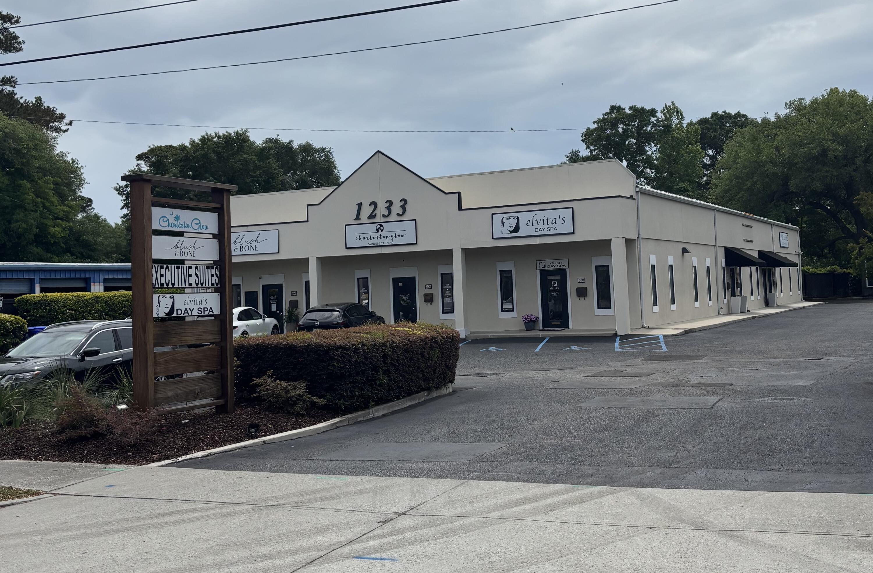 Exterior view of a one-story commercial building with multiple suites and a sign listing businesses.