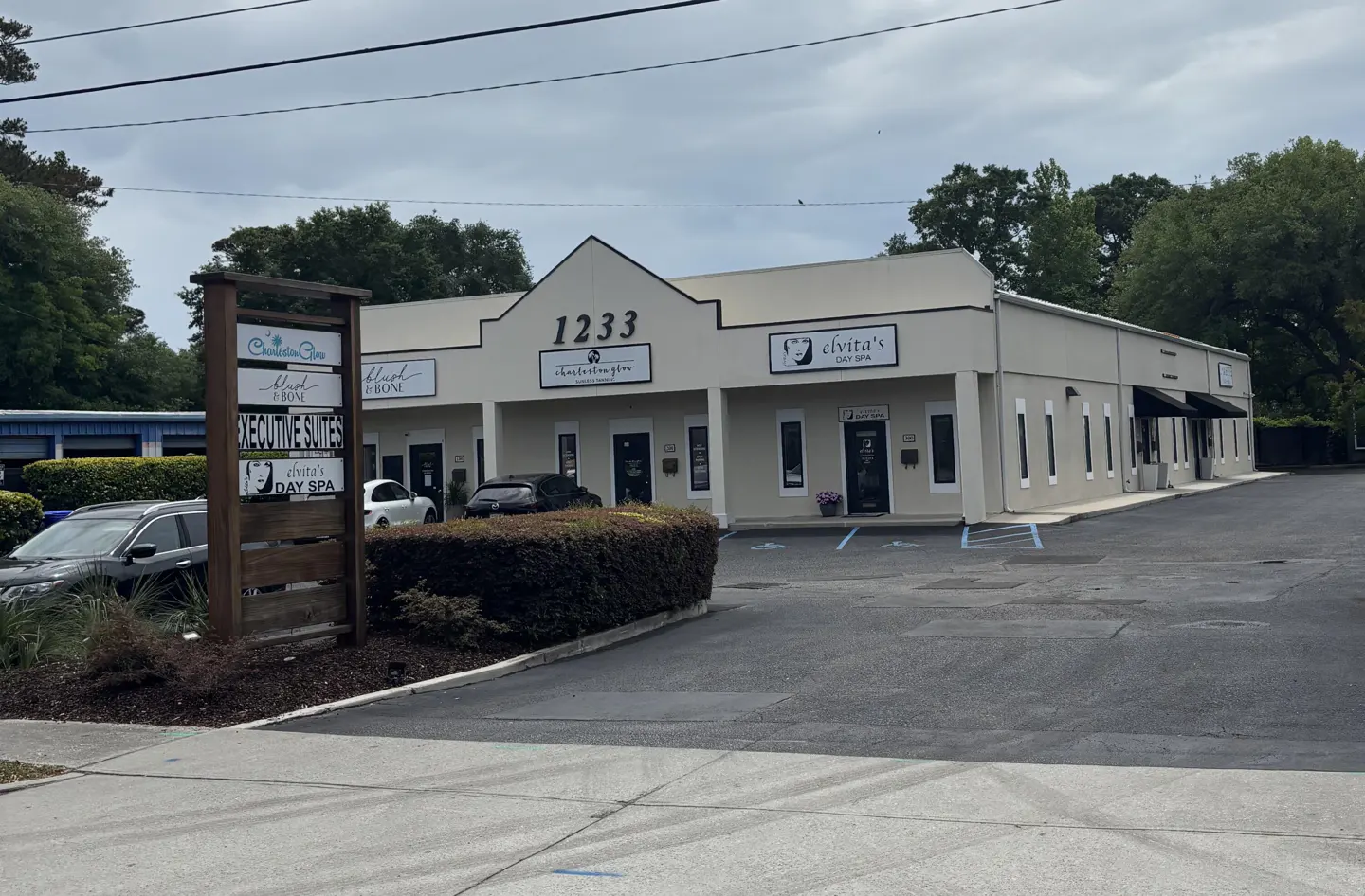 Exterior view of a one-story commercial building with multiple suites and a sign listing businesses.