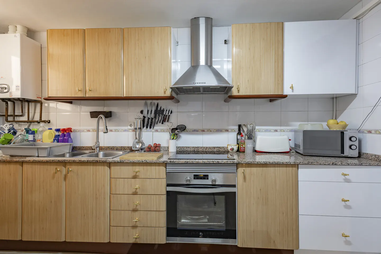 Kitchen with light wood and white cabinets, stainless steel appliances, a tiled backsplash, and a granite countertop.