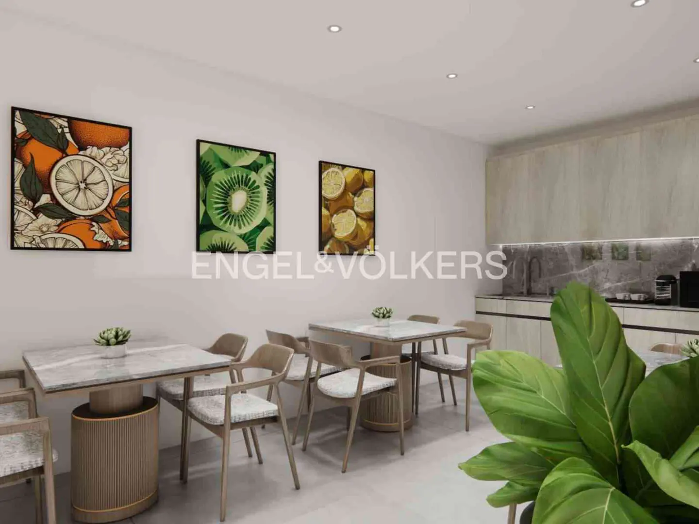 A bright dining area with marble-topped tables, wooden chairs, and fruit-themed art on the white walls. A kitchen area is visible in the background.