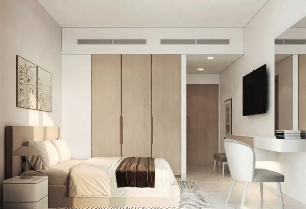 A modern bedroom with a bed, nightstand, art, and a desk with a TV. The color scheme is neutral with beige, white, and gray tones.