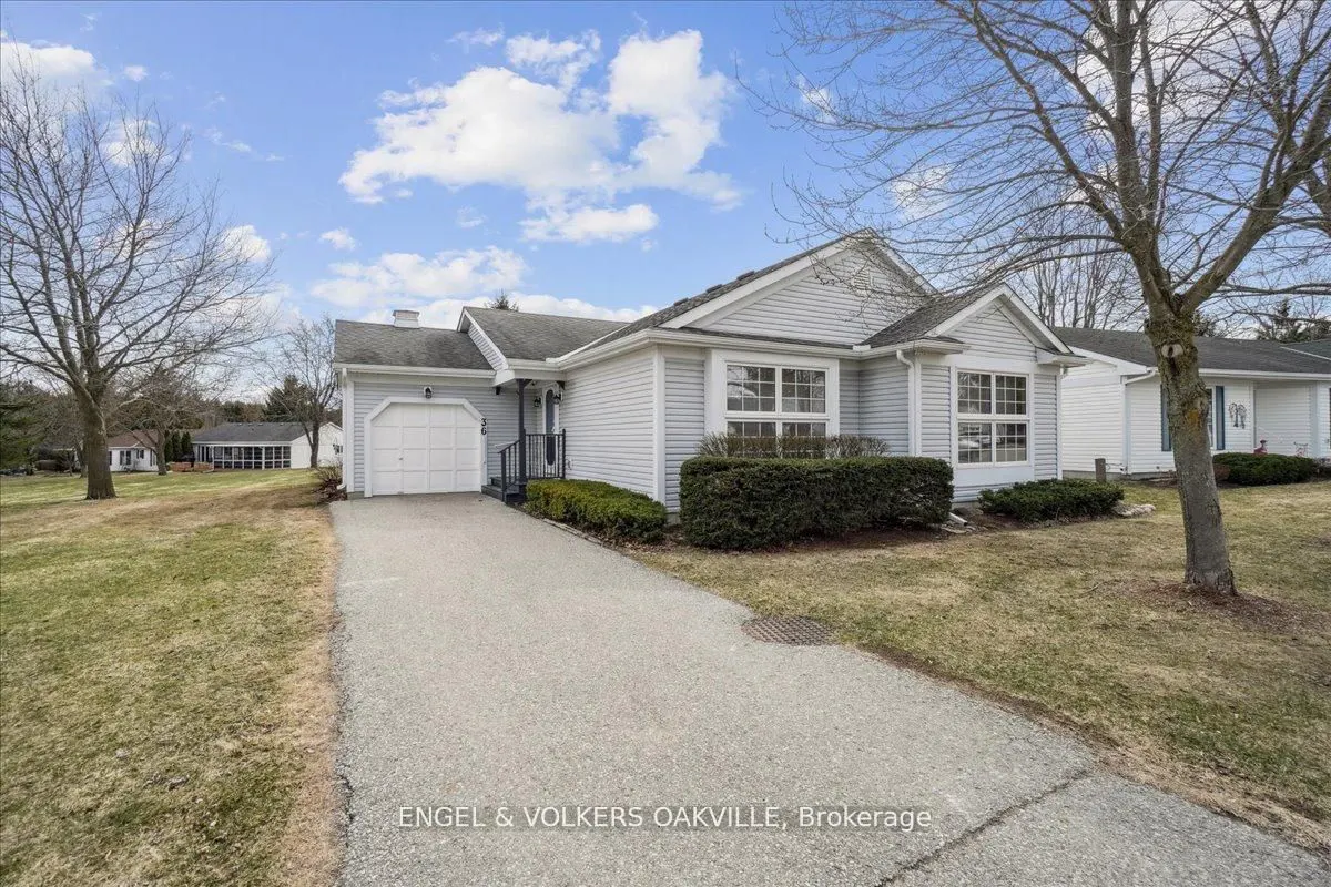 Exterior of a light gray single-story home with a white garage door and a paved driveway. Blue sky with clouds.