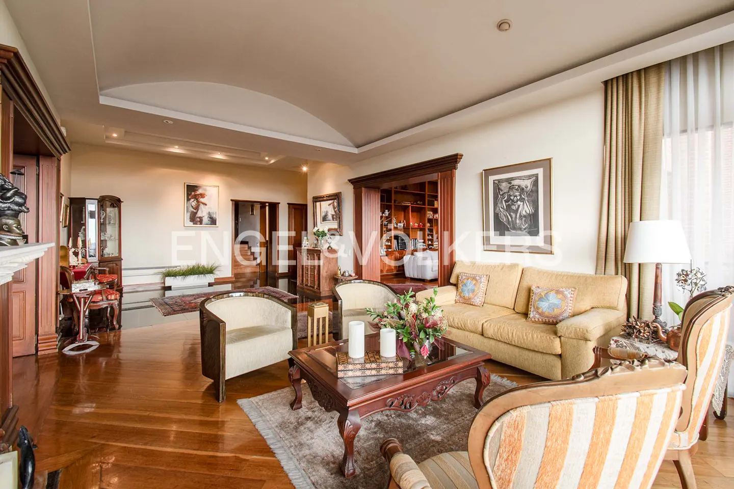 A wide shot of a living room with hardwood floors, a yellow sofa, and a dark wood coffee table.