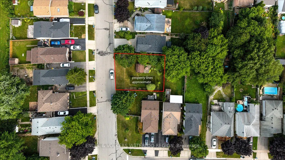 Aerial view of a residential area with a property outlined in red, surrounded by green trees and houses.