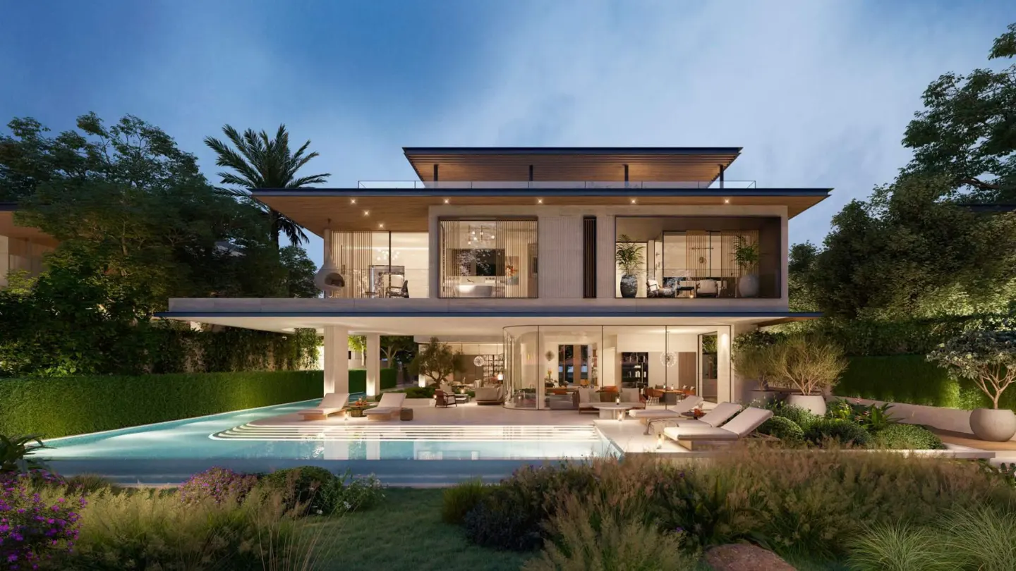 Modern two-story luxury villa at dusk with a glowing infinity pool, outdoor lounge area, and lush landscaped garden.