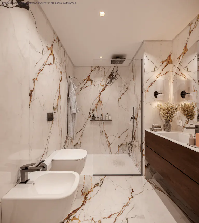 A modern bathroom with white marble walls and floors with brown veining. A glass-enclosed shower, toilet, bidet, and wood vanity are visible.