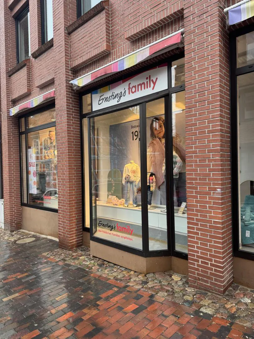 Exterior view of Ernsting's family store with brick facade, black framed windows, and colorful awning.