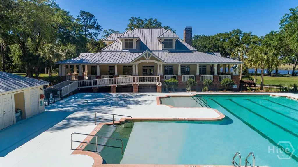 Aerial view of a community pool with a clubhouse in the background on a sunny day.