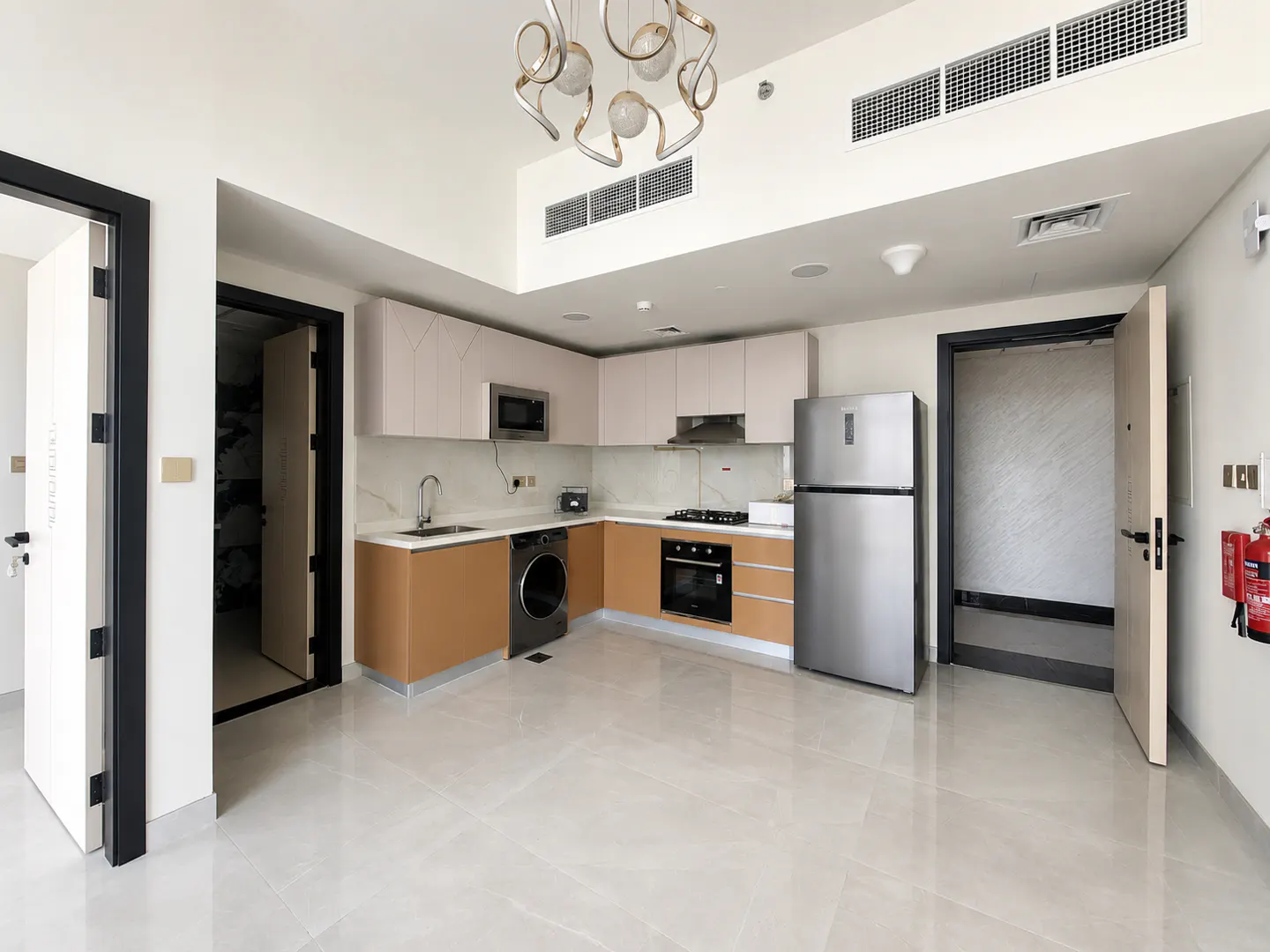 Bright, modern kitchen with stainless steel appliances, light wood cabinets, and a decorative chandelier. Open floor plan with tile flooring.