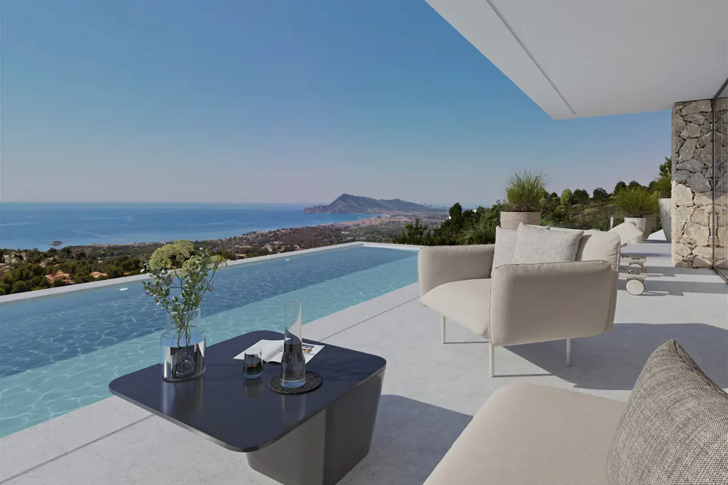 Luxury villa patio with infinity pool overlooking the ocean. Beige chairs and a black table with flowers and drinks.
