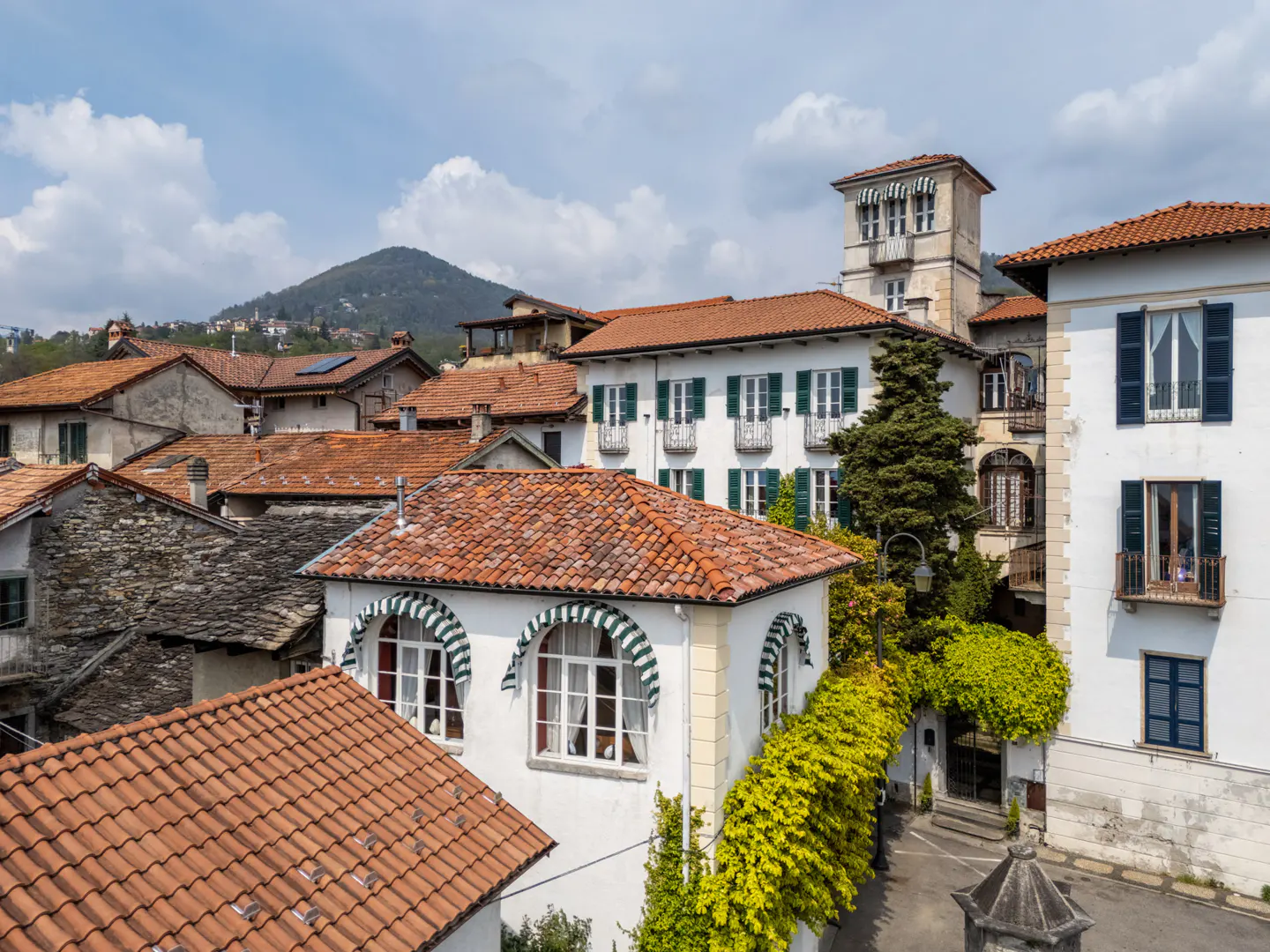 View of a European village with white buildings, red tile roofs, and a mountain backdrop.