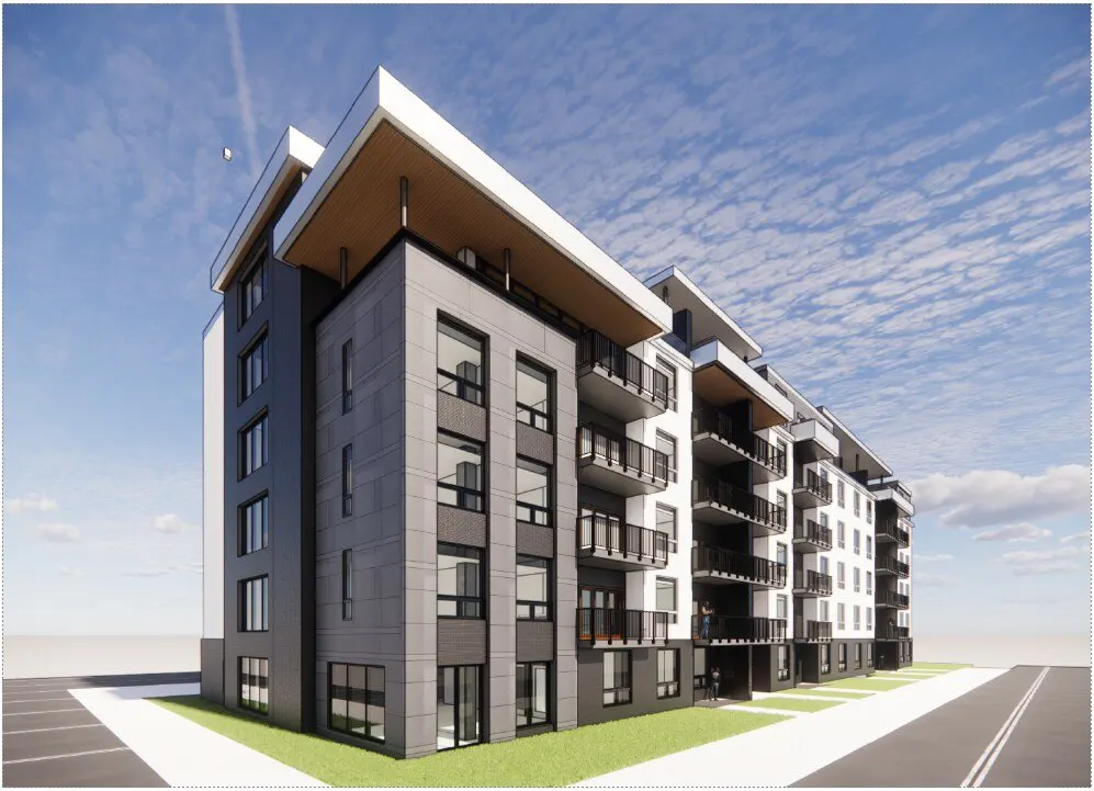 Modern multi-story apartment building with gray and white facade, balconies, and flat roof against a blue sky.