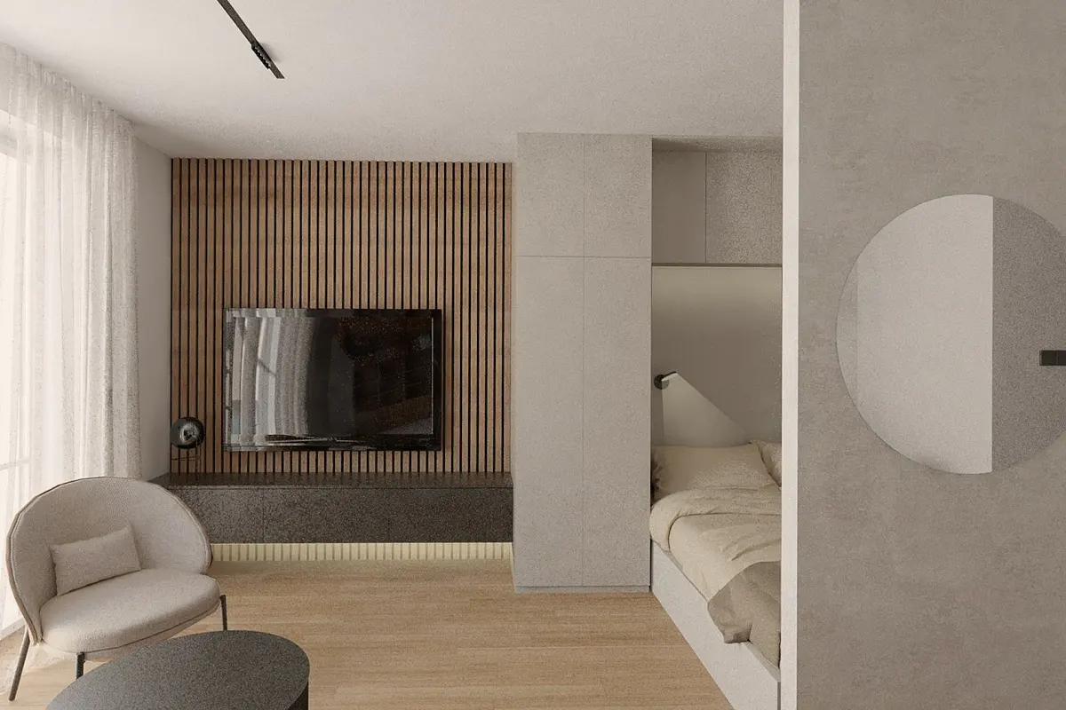 Modern studio apartment with a TV on a wood slat wall, a chair, and a bed nook with a round mirror.