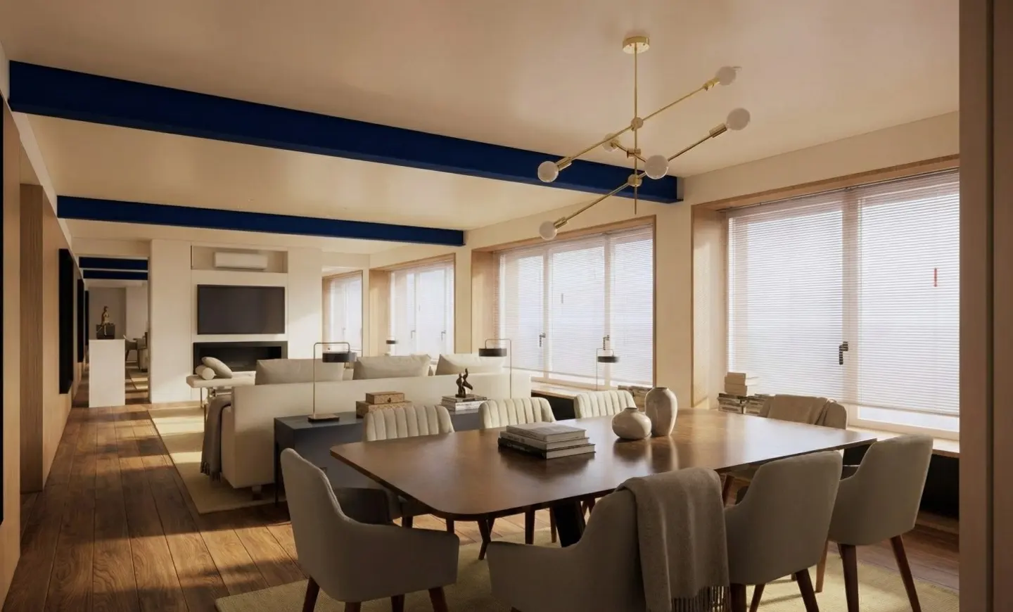 Open-concept living and dining area with wood floors, blue beams, and large windows. A dining table with chairs is in the foreground.