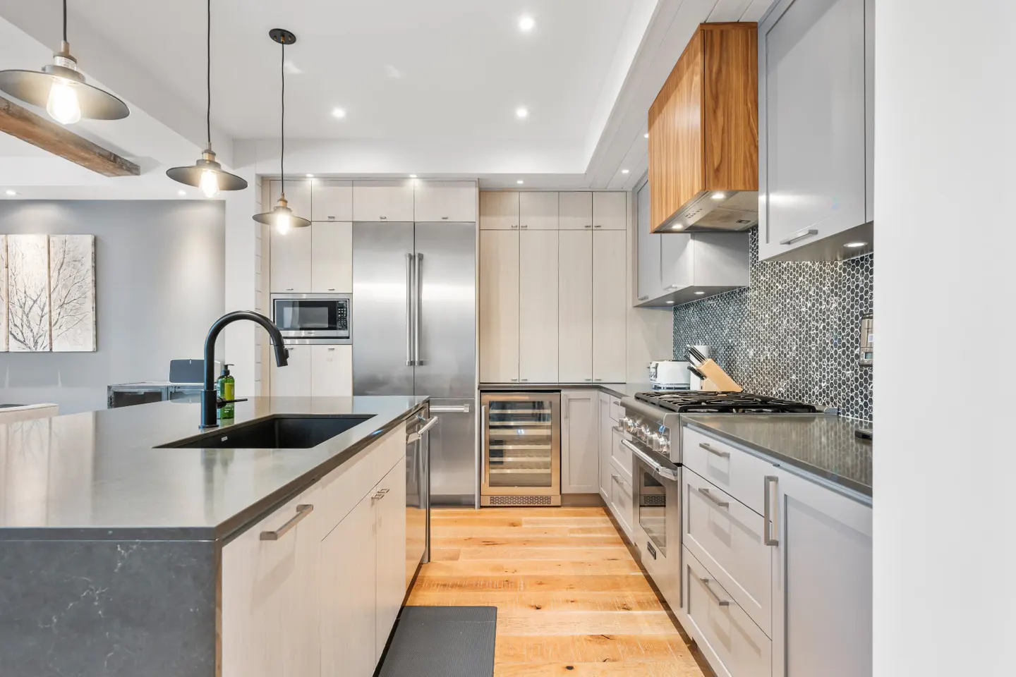 Bright kitchen with wood floors, gray cabinets, stainless steel appliances, and a black sink in the island.