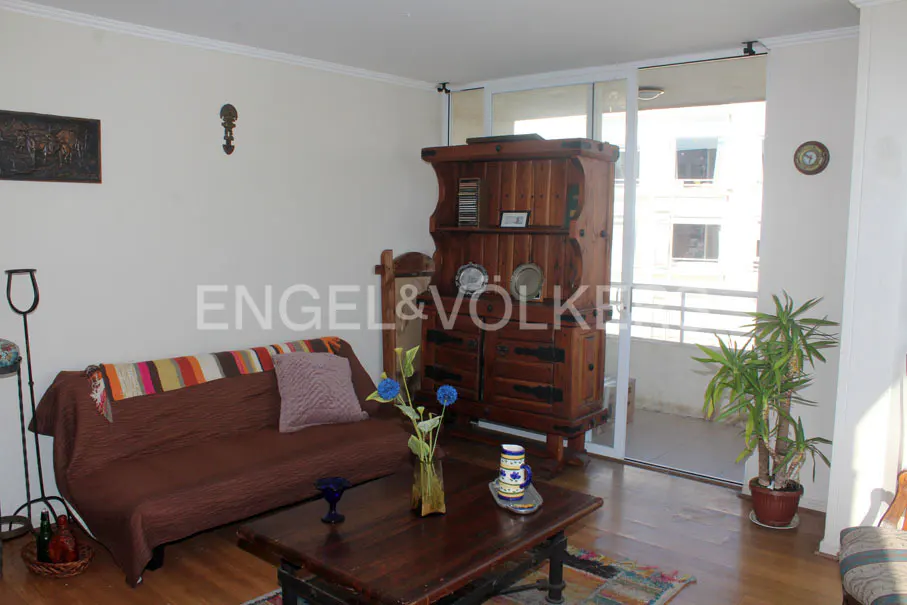 Living room with brown sofa, wooden cabinet, and sliding glass doors to a balcony. A coffee table sits in front of the sofa.